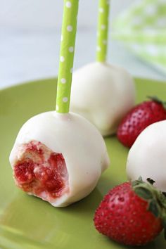 two strawberries and one strawberry are on a green plate with white chocolate covered strawberries