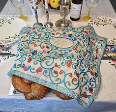 two croissants wrapped in a blanket on a table with wine bottles and glasses