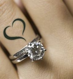 a woman's engagement ring with a heart tattoo on her left hand and a diamond in the middle