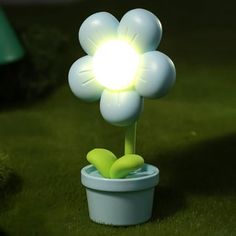 a light up flower in a pot on the ground