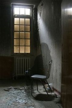 a chair sitting in an empty room next to a window with light coming through it