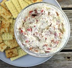 a white plate topped with crackers and a bowl of dip