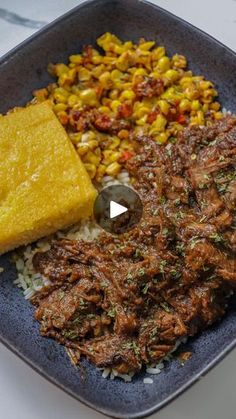 a blue plate topped with rice, corn and meat next to a piece of cheese