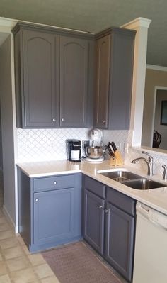 a kitchen with gray cabinets and white counter tops