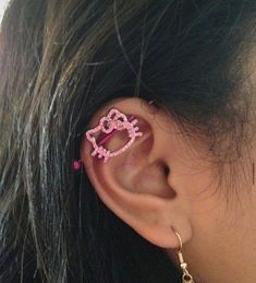 a girl with pink ear piercings has her hair in the shape of a heart