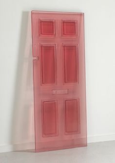 a pink plastic door sitting on top of a white floor in front of a wall