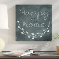 a black and white painting with the words happy at home on it next to a lamp