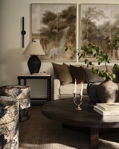 a living room filled with furniture and two paintings on the wall above it's coffee table