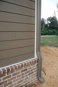 the corner of a house with a brick and metal pole on it's side