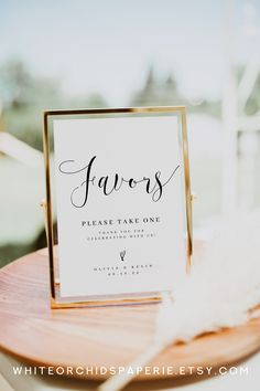 a sign that says favors on it sitting on top of a wooden table next to a white feather