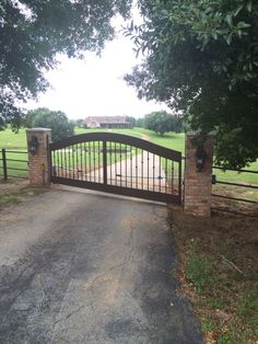 a gated driveway leading to a large grassy field