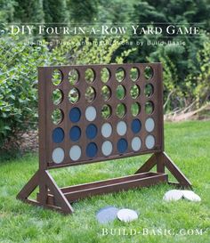 a giant four - sided board game in the grass with trees in the background and bushes to the side