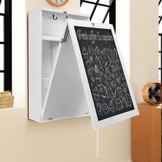 a white chalkboard mounted to the side of a wall in front of a clock