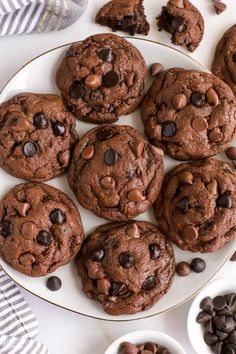 chocolate chip cookies on a white plate with bowls of chocolate chips