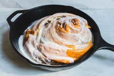 a cinnamon roll in a skillet with icing