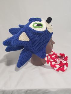 a crocheted hat with an eyeball on it next to a red and white rope