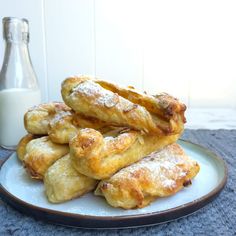 some pastries are stacked on a plate next to a bottle of milk