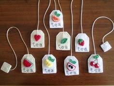 some tea bags are hanging from strings on a table with fruit and veggies written on them