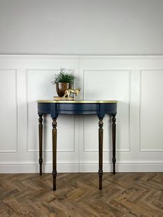 a blue table with a potted plant sitting on it's top next to a wooden floor