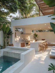 an outdoor kitchen and living room with pool in the middle, surrounded by greenery