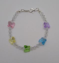 "This beautiful, sparkling, and durable anklet/ bracelet is made with Swarovski Crystal beads and is strung on stainless steel accuflex wire. The lobster claw clasp is made up of steel, pewter, and silver-plated pieces. Color: Pastel Rainbow Shape: Butterflies Small Bracelet - 6\" (very small) Medium Bracelet - 7\" Large Bracelet - 8\" (also works as an anklet for kids) Small Anklet - 9\" Medium Anklet 10\" Large Anklet 11\" (I've seen young girls wear these as necklaces) Anklets can also be mad Clear Bead Bracelet, Swarovski Butterfly, Rainbow Butterflies, Beaded Anklet, Large Bracelet, Small Bracelets, Swarovski Crystal Beads, Color Pastel, Beaded Anklets