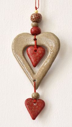 a ceramic ornament with hearts hanging from it's side on a wall