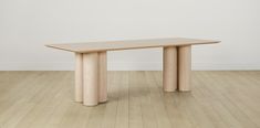 a wooden table sitting on top of a hard wood floor next to a white wall