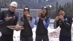 four people standing in the snow eating food