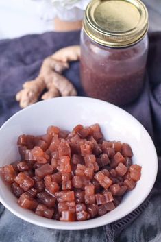 a white bowl filled with chopped carrots next to a jar of ginger paste