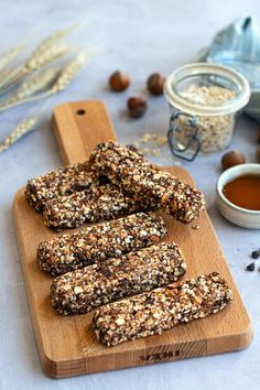 homemade granola bars on a wooden cutting board next to some nuts and other ingredients