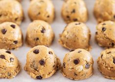 chocolate chip cookie dough balls lined up on a baking sheet, ready to be baked