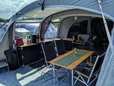 the inside of a tent with tables and chairs set up in front of it for camping