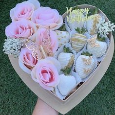 a heart shaped box filled with chocolate covered strawberries and pink roses on top of green grass