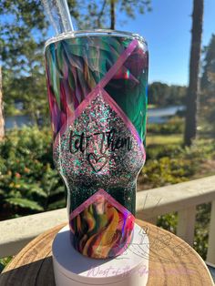 the tumbler cup has been decorated with glitter and is sitting on top of a wooden table