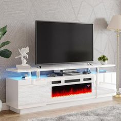 an entertainment center with a television and fire in the fireplace on it's side