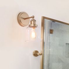 a bathroom with a glass shower door and light fixture on the wall next to it