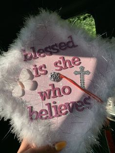 a person holding a pink and white graduation cap with the words, please is she who believe