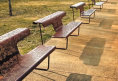 a row of benches sitting next to each other on top of a grass covered field