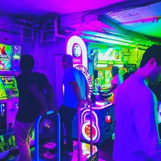 several people playing video games in a brightly lit room with neon lights on the ceiling