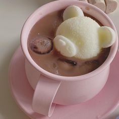 a pink cup filled with ice cream and marshmallows on top of a saucer