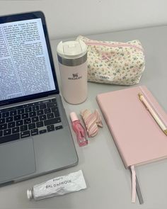 an open laptop computer sitting on top of a desk next to a cup and pen