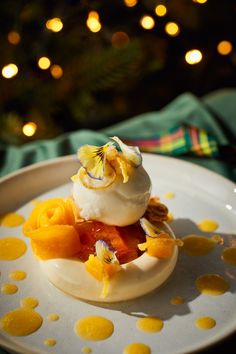 a dessert with fruit and whipped cream on a white plate in front of a christmas tree