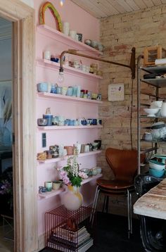 a pink wall with shelves filled with dishes and vases on it's sides