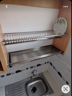 a kitchen sink under a shelf next to a dishwasher