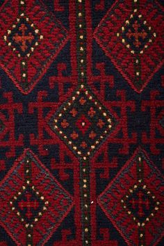 a close up view of a red and black area rug with geometric designs on it