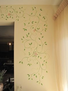 a white wall with green vines and flowers painted on it