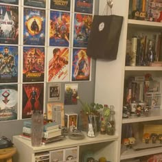 there are many movie posters on the wall behind this bookcase, and in front of it is a shelf full of movies