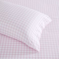 a pink and white checkered bed sheet with pillows