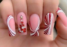 a woman's hand with red and white nail polishes on it, decorated with candy