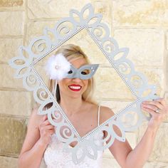 a woman wearing a masquerade and holding up a paper cutout with a flower on it